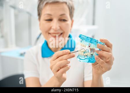 Femme thérapeute dentaire pointant la dent détruite Banque D'Images