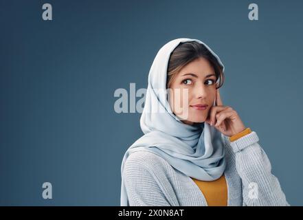 Femme, studio et penser en hijab avec des mains pour la vision avec confiance pour le plan avec des idées. Culture islamique, fierté et fond bleu pour arabe Banque D'Images