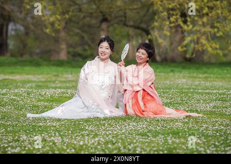 Londres, Royaume-Uni. 13 avril 2024. Météo britannique : deux dames orientales en robe traditionnelle profitent d'un samedi matin chaud à Greenwich Park. Les températures de la ville devraient être au-dessus de la moyenne au cours du week-end. Crédit : Guy Corbishley/Alamy Live News Banque D'Images