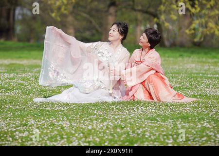 Londres, Royaume-Uni. 13 avril 2024. Météo britannique : deux dames orientales en robe traditionnelle profitent d'un samedi matin chaud à Greenwich Park. Les températures de la ville devraient être au-dessus de la moyenne au cours du week-end. Crédit : Guy Corbishley/Alamy Live News Banque D'Images