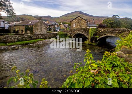 Le pittoresque pont en arc de pierre dans la ville de Beddgelert, avec les montagnes d'Eryri s'élevant en arrière-plan et des feuilles de lierre au premier plan Banque D'Images