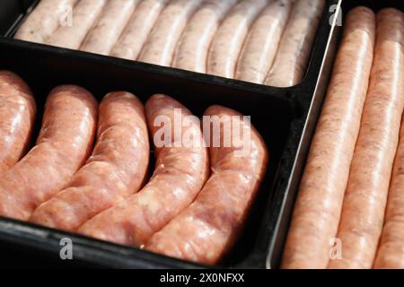 Assortiment de saucisses fraîches pour la préparation du barbecue dans un emballage noir. BARBECUE. Fête barbecue d'été festive. À l'extérieur. Gros plan. Banque D'Images