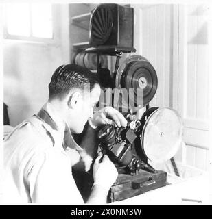 Un éditeur de film de l'Army film and Photographic Unit examine une séquence de film sur un moviola, capturée dans un négatif photographique de l'armée britannique. Banque D'Images
