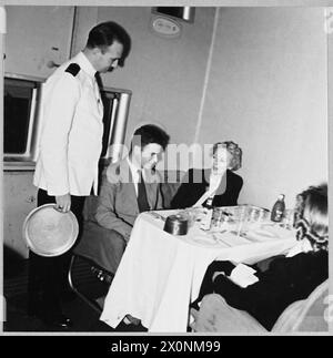 LES LIGNES AÉRIENNES CIVILES BRITANNIQUES EN TEMPS DE GUERRE - pour l'histoire voir CH.14022 photo (publiée en 1944) spectacles - le dîner est servi aux passagers dans le fumoir d'un hydravion Boeing lors d'un vol transatlantique de la BOAC. On observera que tous les équipements de luxe ont été retirés de l'intérieur en temps de guerre. Négatif photographique, Royal Air Force Banque D'Images