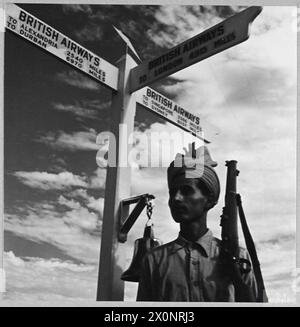 LIGNES AÉRIENNES CIVILES BRITANNIQUES EN TEMPS DE GUERRE - pour l'histoire voir CH.14012 photo (publiée en 1944) montre - un garde indien à l'aéroport maritime de Karachi sous l'un des panneaux les plus éloignés du monde à l'extérieur des bureaux de réception de la base BOAC. Négatif photographique, Royal Air Force Banque D'Images