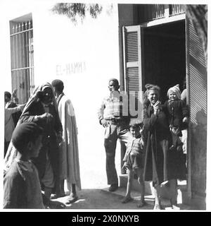 EL HAMMA À GABÈS. La 8ème ARMÉE AVANCE PAR El HAMMA À GABÈS - les habitants français regardant les garçons de la 8ème armée passer par El Hamma. A droite, une femme française aide son bébé à donner le nouveau célèbre signe de la victoire. Négatif photographique, Armée britannique Banque D'Images