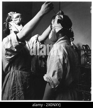 LE SERVICE DE TRANSFUSION SANGUINE DE L'ARMÉE - ATS mettant des blouses stériles et des masques avant d'entrer dans la salle stérile. Noms : Ptes. Coleman et Skimmins, ATS. Négatif photographique, Armée britannique Banque D'Images