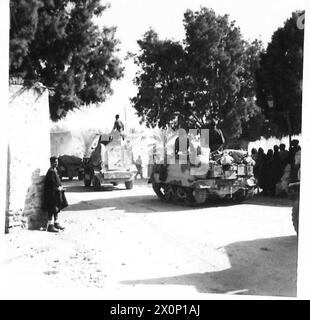 EL HAMMA À GABÈS. AVANCE DE la 8ème ARMÉE À TRAVERS El HAMMA JUSQU'À GABÈS - le matin du 29 mars après un bombardement d'artillerie lourde qui a duré toute la nuit, l'ennemi a été contraint d'évacuer El Hamma, une position importante au sud de Gabès ... Les images montrent des indigènes regardant avec intérêt les premiers véhicules blindés à passer à travers à la poursuite du négatif photographique ennemi, l'armée britannique Banque D'Images