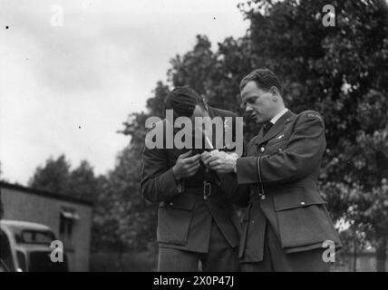 L'ARMÉE DE L'AIR POLONAISE EN GRANDE-BRETAGNE, 1940-1947 - le pilote Jan 'Donald Duck' Zumbach du 303e Escadron polonais de chasse obtenant une lumière du pilote-officier Zygmunt Wodecki, le médecin de l'Escadron, pendant une pause cigarette. Photographie prise à la RAF Northolt ou à la RAF Speke, juillet 1941 Force aérienne polonaise, Force aérienne polonaise, 303e escadron de chasse 'Kościuszko', Zumbach, Jan Eugeniusz Ludwig, Wodecki, Zygmunt Banque D'Images