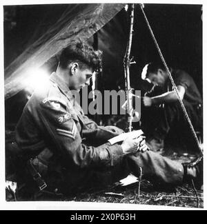 Un ÉQUIPAGE DE CHURCHILL SE PRÉPARE À LA BATAILLE LA VIE D'Un ÉQUIPAGE DE CHARS CHURCHILL - le Cpl Walmsley est assis à l'entrée de sa tente pour lire ses lettres à la lumière d'une lanterne tempête. Négatif photographique, Armée britannique, 21e groupe d'armées Banque D'Images