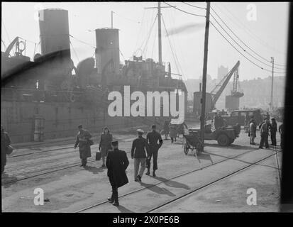 TRAIN DE BATEAUX POUR PARIS : TRANSPORT EN TEMPS DE GUERRE, 1945 - Une scène animée sur le quai quelque part en France, peut-être Boulogne. Le personnel de service et les civils peuvent être vus débarquer, après leur voyage de Newhaven. Ils ont commencé leur voyage à Londres Victoria, et ont voyagé en train jusqu'à Newhaven avant d'embarquer sur ce navire pour traverser la Manche. Un deuxième train les attend pour les emmener à Paris. Selon la légende originale, le navire accoste vers une heure et le train attend à côté. Les passagers se rendent à leur train - c'est un processus tranquille, très diff Banque D'Images