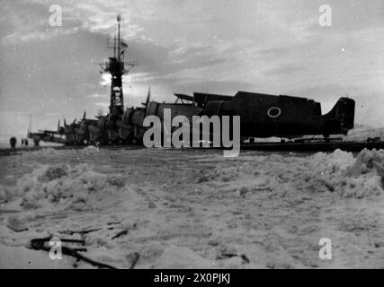 CONVOI BRITANNIQUE EN RUSSIE. LE 1945, À BORD DU PORTE-AVIONS D'ESCORTE BRITANNIQUE HMS CAMPANIA LORS D'UN CONVOI À DESTINATION DE LA RUSSIE LORSQUE LE TEMPS ARCTIQUE ÉTAIT AMER. - Les avions se réchauffent sur le pont d'envol enneigé de CAMPANIE prêt pour une grève Banque D'Images