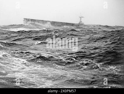 CONVOI BRITANNIQUE EN RUSSIE. DU 4 FÉVRIER AU 2 MARS 1945. À BORD DU CROISEUR HMS BELLONA SUR UN CONVOI À DESTINATION ET EN PROVENANCE DE LA RUSSIE. SUR LE CONVOI, UN U-BOOT A ÉTÉ COULÉ ET DE NOMBREUX AVIONS ALLEMANDS ONT ÉTÉ ABATTUS. - Le porte-avions d'escorte HMS NARIANA avec ses arcs cachés par la mer lourde Banque D'Images