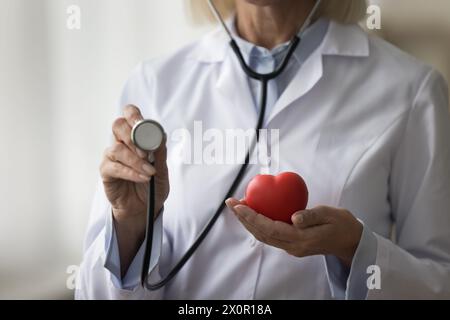 Médecin féminin inconnu tenant dans les mains coeur et outil stéthoscope Banque D'Images