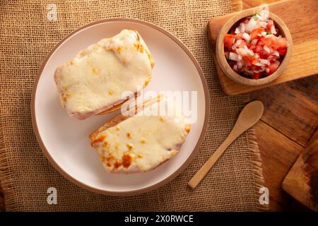 Molletes. Recette mexicaine à base de pain bolillo fendu dans le sens de la longueur, tartiné de haricots frits et de fromage gratiné, ajoutant de la sauce Pico de gallo et un peu de pro Banque D'Images