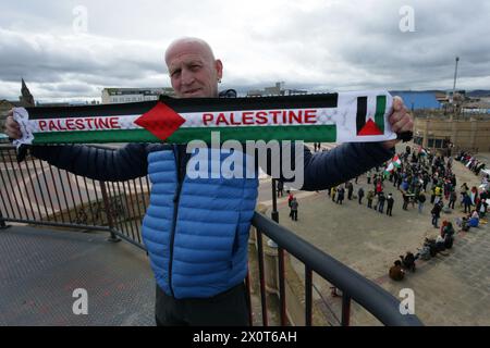 Rhyl, Royaume-Uni. 13 avril 2024. Un manifestant tient une écharpe palestinienne pendant la manifestation. Plus de 150 partisans pro-palestiniens de partout au pays de Galles ont manifesté dans les rues pour exiger un cessez-le-feu à Gaza et mettre fin au génocide. Crédit : SOPA images Limited/Alamy Live News Banque D'Images