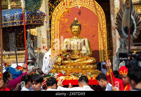 Chiang mai, Thaïlande. 13 avril 2024. Les thaïlandais offrent des fleurs lors de la procession de la statue de Bouddha de Phra Bouddha Sihing pour marquer les célébrations de Songkran au temple Wat Phra Singh Woramahaviharn. Le festif Songkran est également connu comme le festival de l'eau qui est célébré le jour du nouvel an traditionnel thaïlandais chaque année le 13 avril en pulvérisant de l'eau et en jetant de la poudre sur les visages des autres comme un signe symbolique de nettoyage et de lavage des péchés de l'année dernière. (Photo de Pongmanat Tasiri/SOPA images/Sipa USA) crédit : Sipa USA/Alamy Live News Banque D'Images