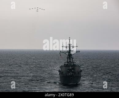 EN MER (11 avril 2024) le destroyer USS Russell (DDG 59) de classe Arleigh Burke et les avions du Carrier Air Wing (CVW) 11 naviguent et volent en formation lors d'un exercice trilatéral avec le porte-avions USS Theodore Roosevelt (CVN 71) de classe Nimitz, le 11 avril 2024. Cet exercice trilatéral a permis aux forces maritimes du Japon, de la République de Corée et des États-Unis de s’entraîner ensemble afin d’améliorer la coordination sur la connaissance du domaine maritime et d’autres intérêts communs en matière de sécurité. Le Theodore Roosevelt Carrier Strike Group est déployé dans la zone d'opérations de la 7e flotte des États-Unis à l'appui d'une zone libre Banque D'Images