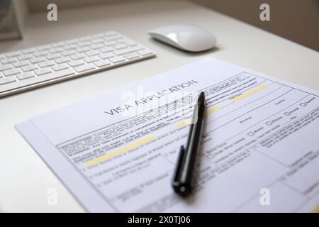 Gros plan d'une poêle noire sur le document de demande de visa, sur une table avec un clavier d'ordinateur et une souris Banque D'Images