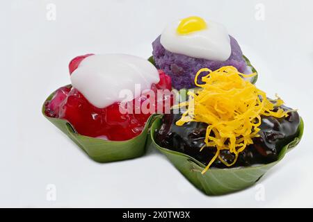 Gros plan de 3 desserts thaïlandais Khanom Tako « à l'envers », avec une variété de garnitures : taro violet, riz gluant noir et chesnuts à l'eau rubis rouge Banque D'Images