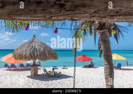 Arashi Beach Aruba avec parasols et amateurs de plage vus du café Banque D'Images