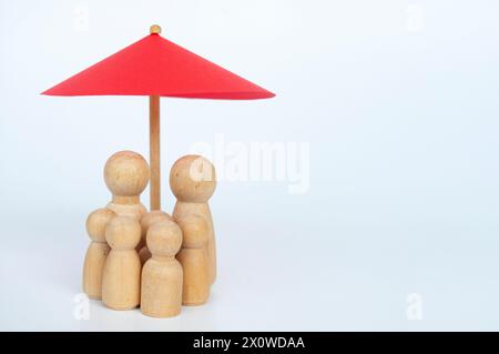 Parapluie jouet rouge et poupée familiale en bois figure un fond blanc. Concept de couverture d'assurance-vie. Banque D'Images