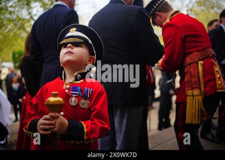 Un jeune garçon en réplique uniforme rejoint les membres des Scots Guards alors qu'ils se rassemblent avant le défilé du dimanche noir, à la chapelle du Guards Museum à Wellington Barracks, Westminster, Londres. Date de la photo : dimanche 14 avril 2024. Banque D'Images