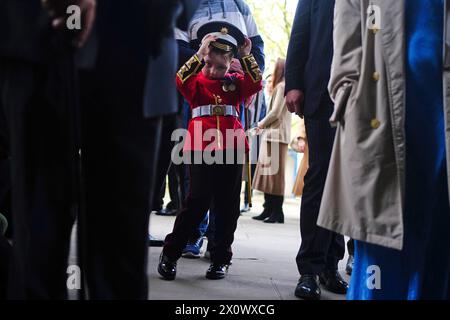 Un jeune garçon en réplique uniforme rejoint les membres des Scots Guards alors qu'ils se rassemblent avant le défilé du dimanche noir, à la chapelle du Guards Museum à Wellington Barracks, Westminster, Londres. Date de la photo : dimanche 14 avril 2024. Banque D'Images