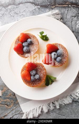 Crêpes japonaises moelleuses avec des baies fraîches gros plan sur une assiette sur la table. Vue de dessus verticale Banque D'Images
