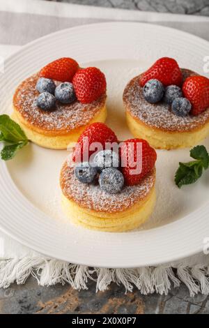 Crêpes japonaises moelleuses avec des baies fraîches gros plan sur une assiette sur la table. Vertical Banque D'Images