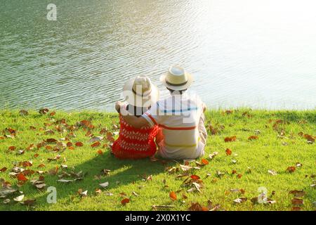 Couple se relaxant ensemble sur le bord du lac dans la lumière chaude du soleil Banque D'Images