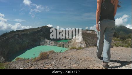 Une femme se tient au sommet d'une montagne, regardant à travers une vue imprenable sur un lac niché dans la vallée ci-dessous. Le paysage comprend un lac de cratère volcanique aux Philippines. Banque D'Images