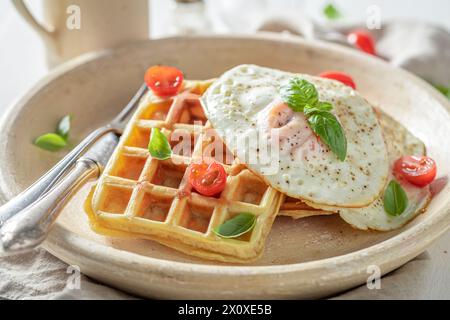 Gaufres maison et chaudes avec tomates cerises et œufs au plat. Œufs frits et gaufres pour le petit déjeuner. Banque D'Images