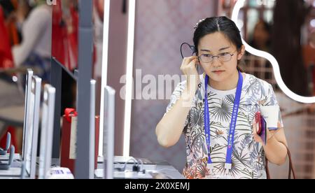 (240414) -- HAIKOU, 14 avril 2024 (Xinhua) -- Un visiteur essaie un écouteur au stand du Shokz de Chine lors de la quatrième exposition internationale des produits de consommation de Chine (CICPE) à Haikou, capitale de la province de Hainan, dans le sud de la Chine, le 14 avril 2024. Un lot de marques nationales ont attiré beaucoup de visiteurs à l'expo. (Xinhua/Yang Guanyu) Banque D'Images