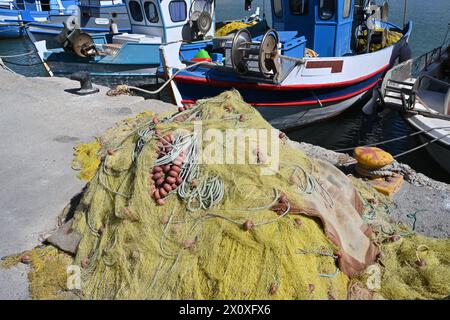 Filet de pêche jaune avec bouées brunes placé sur le quai devant les bateaux de pêche. Il y a beaucoup d'espace de copie. Banque D'Images