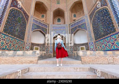 Vue arrière de jeune femme à Boukhara, Ouzbékistan Mir-i-Arab Madrasa Kalyan minaret et tour. Traduction sur la mosquée : 'Mosquée POI Kalyan' Banque D'Images