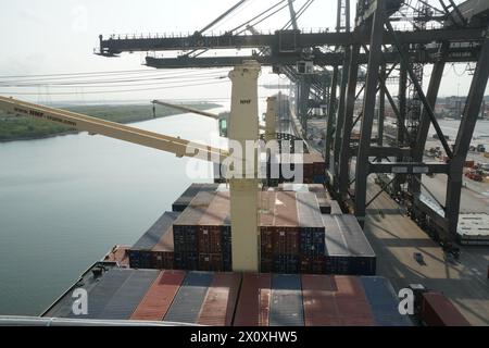 Porte-conteneurs équipés de grues lors des opérations de chargement et de déchargement de cargaison par des portiques manoeuvrés par des débardeurs. Banque D'Images