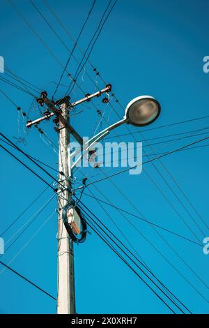 Lampadaire avec poteau électrique et fils électriques désordonnés, vue à faible angle Banque D'Images
