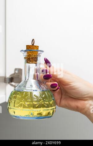 femme au foyer sort une bouteille en verre d'huile de tournesol de l'armoire de cuisine. bouteille en verre avec huile de cuisson. bouteille d'huile d'olive. homme tenant une bouteille de Banque D'Images