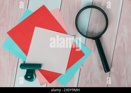 Papier adhésif coloré avec loupe sur bureau en bois. Banque D'Images