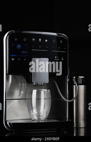 Machine à café sur fond sombre, gros plan. Cafetière moderne avec tasse en verre. Appareils de cuisine Banque D'Images