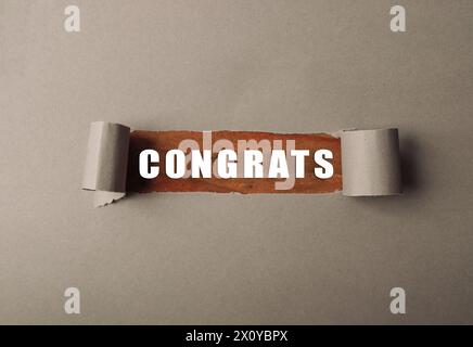 Un morceau de papier déchiré avec le mot félicitations écrit dessus Banque D'Images
