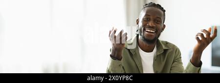 Joyeux homme afro-américain parlant à la caméra et faisant des gestes Banque D'Images