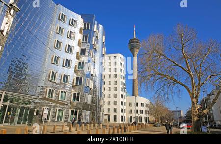 Düsseldorf (Medienhafen), Allemagne - 1er mars. 2021: Vue sur les maisons de Gehry avec une façade en aluminium métallique futuriste et argenté avec tour de télévision Banque D'Images