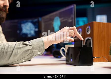Ingénieur logiciel insérant le disque dans l'ordinateur avec l'IA auto-consciente voyous, prévoyant de l'utiliser pour le plan diabolique. Gros plan de l'homme mettant la cartouche contenant un robot d'intelligence artificielle infecté par des logiciels malveillants dans le PC Banque D'Images