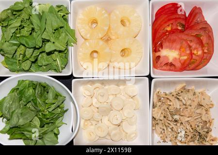 Une variété d'aliments sont exposés dans des bols blancs, y compris des épinards, des tomates, des ananas et des champignons. Les bols sont disposés de manière à ce que le Banque D'Images