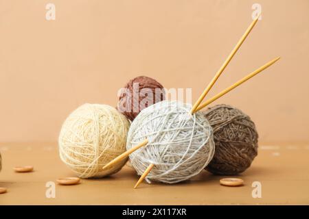 Boules de fil, aiguilles tricotées et boutons sur table en bois brun Banque D'Images