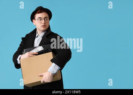 Espion masculin avec pistolet dans la boîte sur fond bleu Banque D'Images