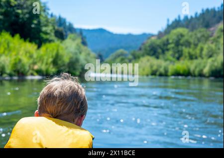 Focus sélectif sur un enfant descendant la sauvage et pittoresque Rogue River tout en portant un gilet de sauvetage Banque D'Images