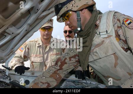 Le sergent d'état-major Mark Scott, 3/7 Cav., donne des instructions à un soldat de l'armée irakienne alors qu'il effectue une vérification préalable au combat sur son véhicule au Camp Volunteer, en Irak, CA. 24 janvier (2003, date par métadonnées) Banque D'Images